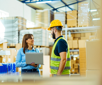 Warehouse workers discussing with a laptop.