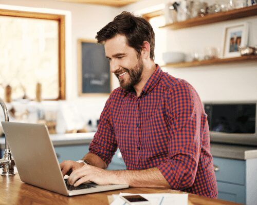 Man smiling while using a laptop.